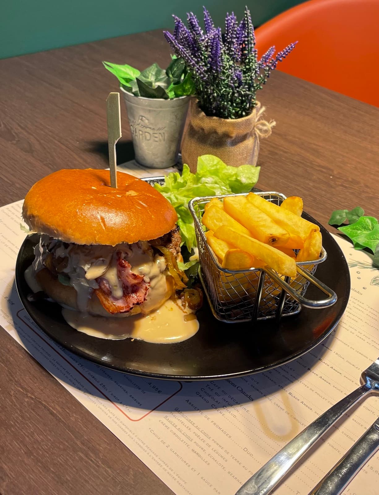 Burger maison au bacon nappé de sauce, frites servies en panier